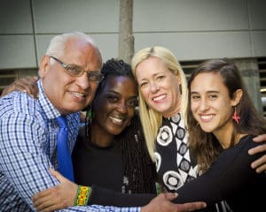 Four people group hugging and smiling for picture