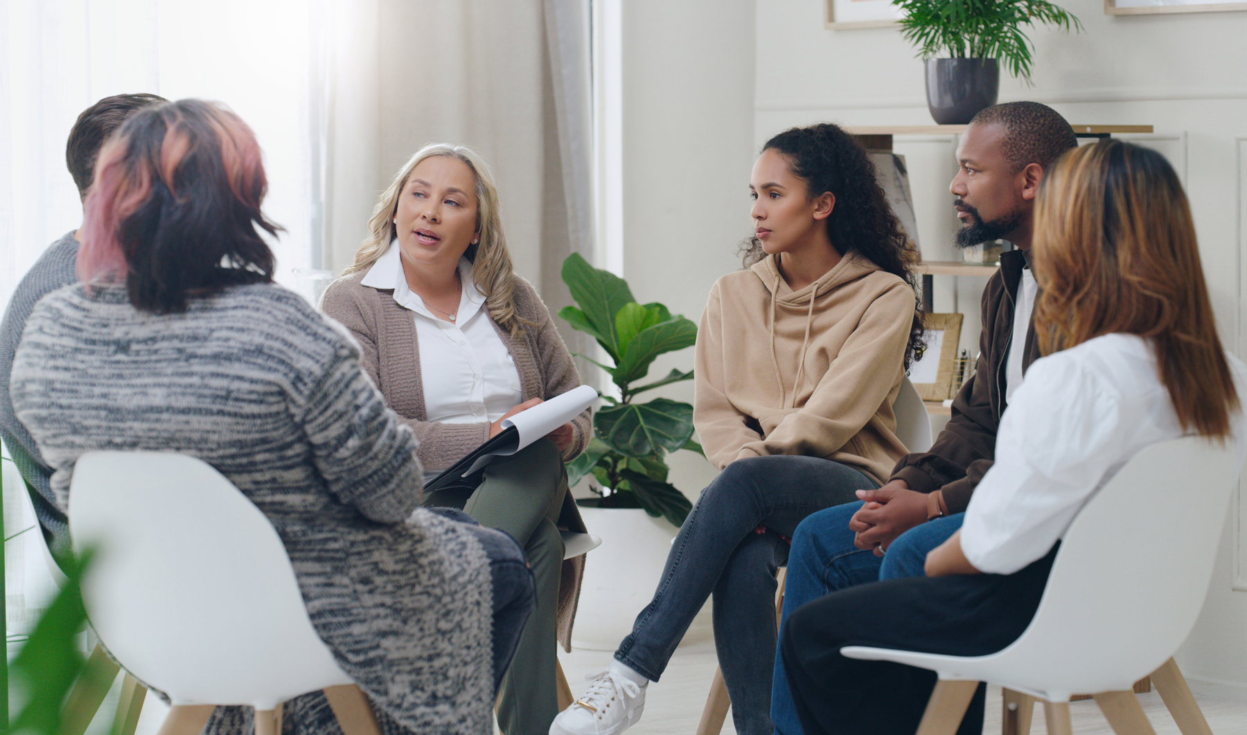 A diverse group of individuals engaged in a discussion while sitting in a circle.