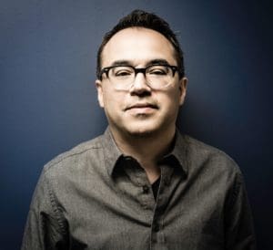 Picture of a man in nice dress shirt and tie, with glasses and black hair