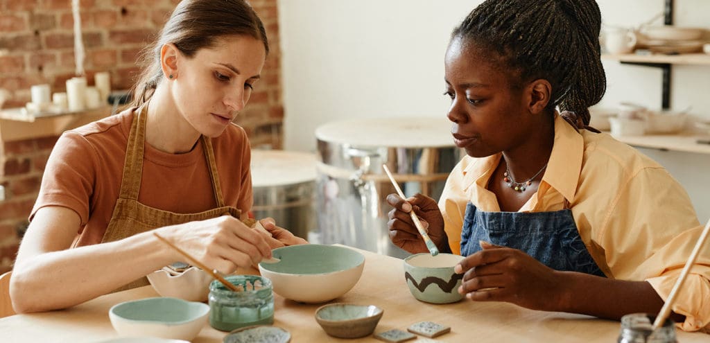 2 individuals painting clay pots