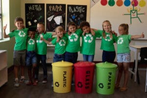 Children in a classroom with green recycling shirts.