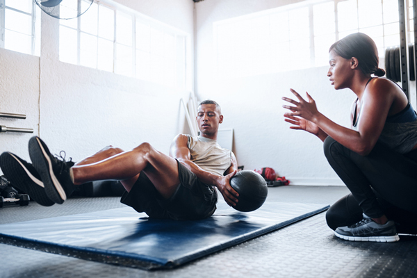 A man and woman are engaged in exercise routines at a gym, showcasing their commitment to fitness and health.